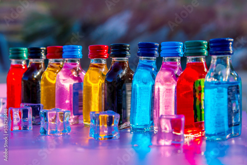 Colorful shorts set, several miniature bottles of different drinks prepared for a pool party with ice cubes