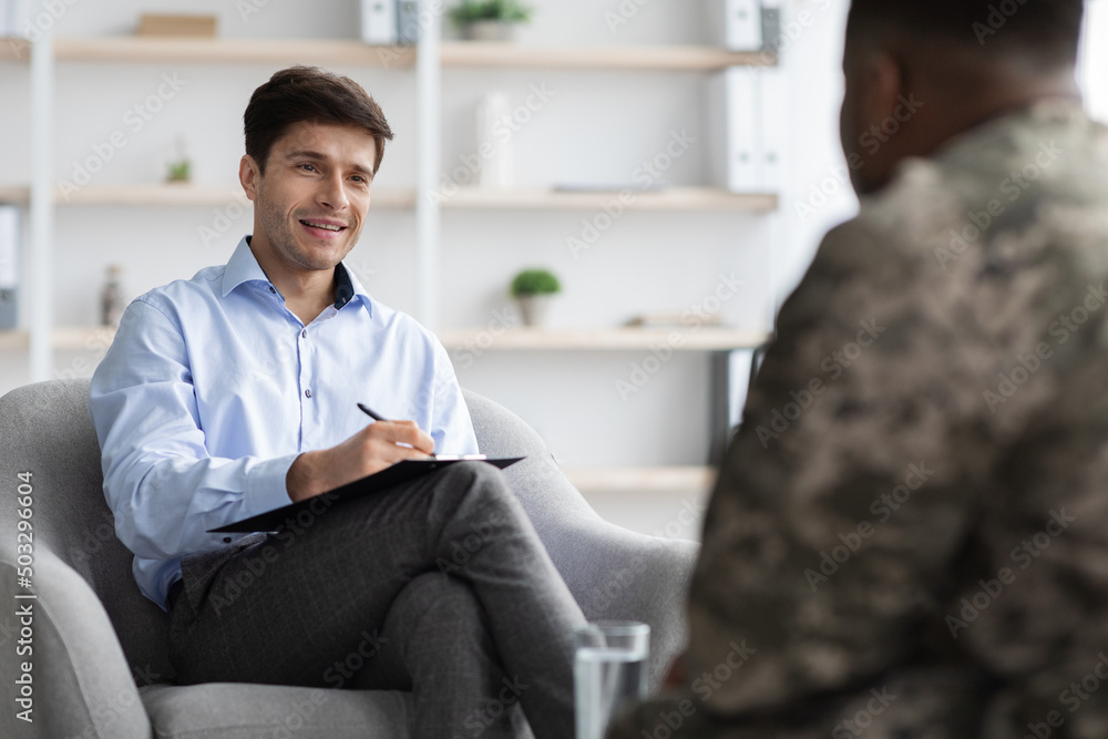 Friendly young man psychologist having conversation with soldier - obrazy, fototapety, plakaty 
