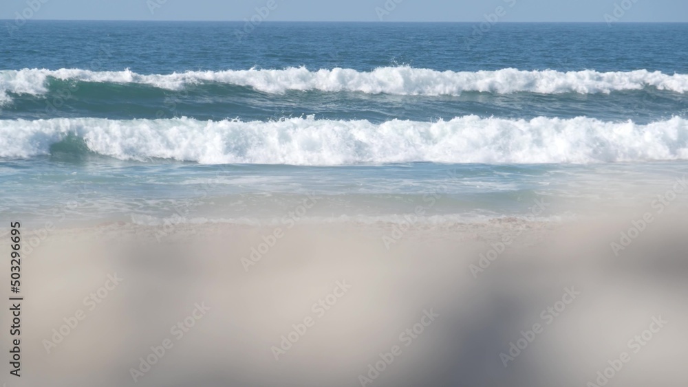 Fototapeta premium Big blue ocean waves crashing on beach, California pacific coast, USA. Sea water foam and white sand. Summertime shore aesthetic. Surfing vibes, seascape near Los Angeles. Seamless looped cinemagraph.