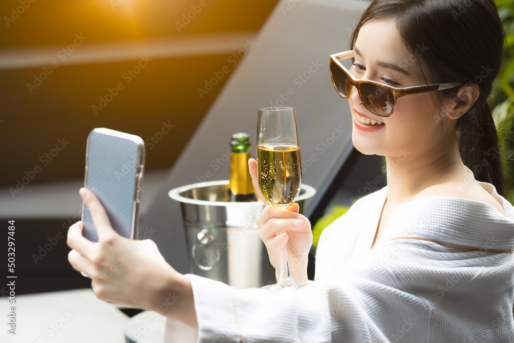 Beautiful girl holding glass of champagne and talking on phone with her friend for celebrating in hotel or resort Beaty young asian woman taking photo selfie for showing her lifestyle on social media Beautiful girl holding glass of champagne and talking on phone with her friend for celebrating in hotel or resort Beaty young asian woman taking photo selfie for showing her lifestyle on social media