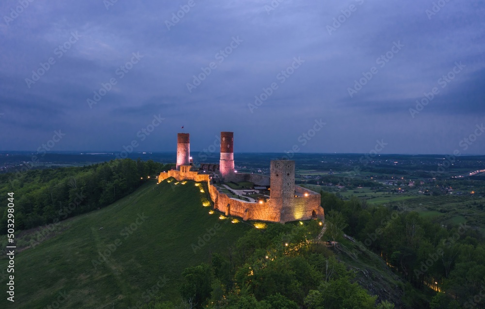 Aerial drone night view over the colorful, illuminated Chęciny Castle (Kielce County, Świętokrzyskie Voivodeship) in Poland