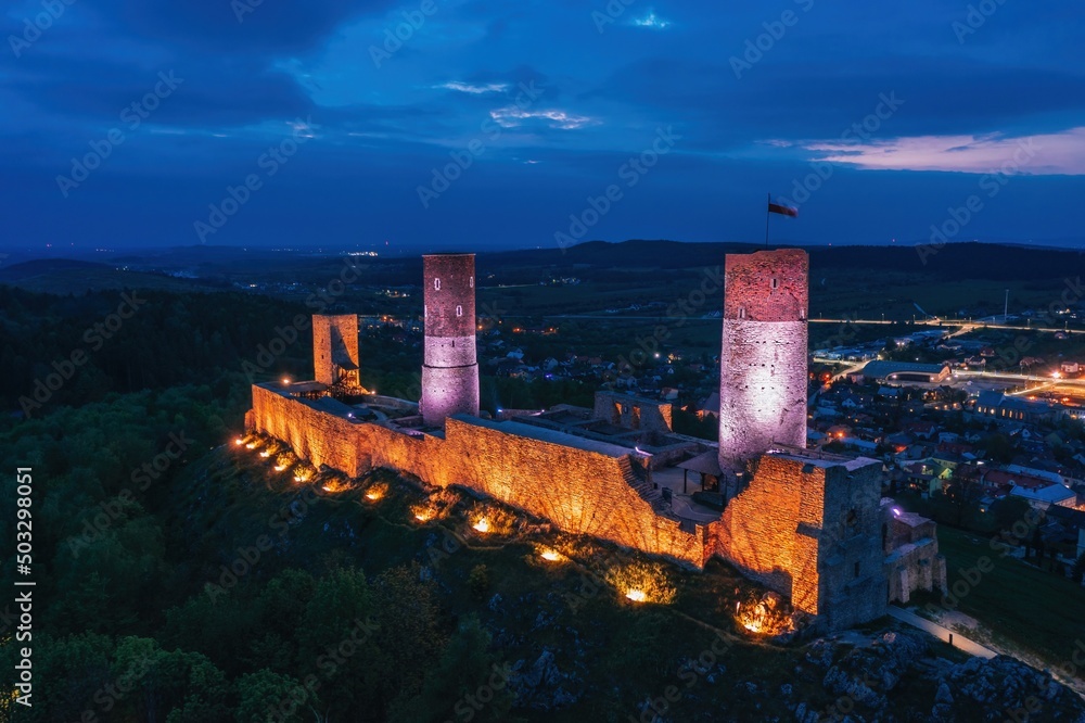 Aerial drone night view over the colorful, illuminated Chęciny Castle (Kielce County, Świętokrzyskie Voivodeship) in Poland
