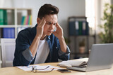 Stressed Young Male Entrepreneur Suffering Headache While Sitting At Desk In Office