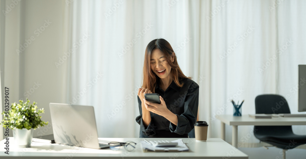 Fototapeta premium Portrait of happy young business asian woman celebrating success with arms up. positive expression, sucess in business concept