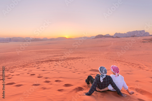 A young couple is watching at sunrise over wadi rum desert in Jordan photo