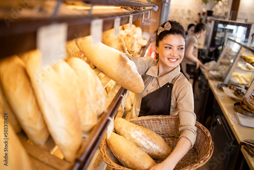 Deli worker selling bread to the customer in supermarket bakery department.