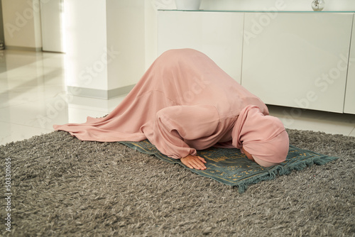 Vászonkép Muslim woman bowing down and prostrating on praying carpet