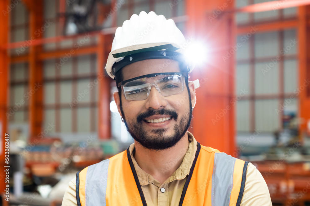 Selective focus at Caucasian men engineer supervisor, wearing safety equipment. While doing audit for quality and safety control inside of factory area. With blurred background of heavy machine. Selective focus at Caucasian men engineer supervisor, wearing safety equipment. While doing audit for quality and safety control inside of factory area. With blurred background of heavy machine.