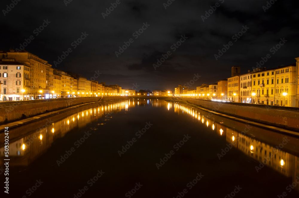 Arno river among the Pisa lights and a cloudy night sky after a rainy day.