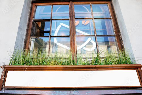 фотографія Empty white banner in wooden frame with mock up space fixed on facade of street
