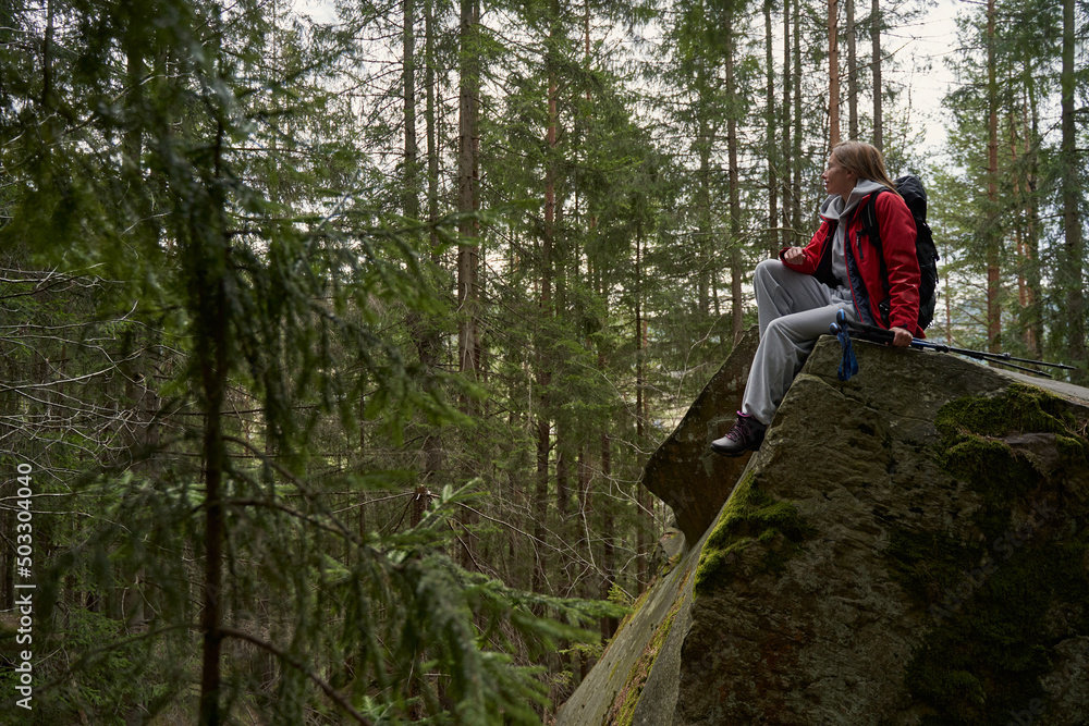 Woman tourist relaxing on rock top and looking at forest Woman tourist relaxing on rock top and looking at forest