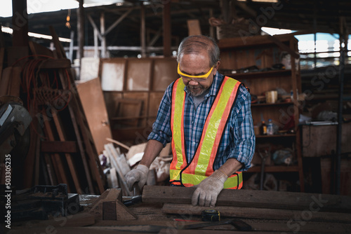 An elderly carpenter works the wood with meticulous care.