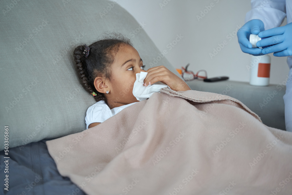African American girl looks at the package of pills held by the doctor African American girl looks at the package of pills held by the doctor