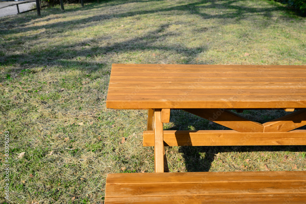 Fototapeta premium Empty wooden picnic table with bench in park on sunny day