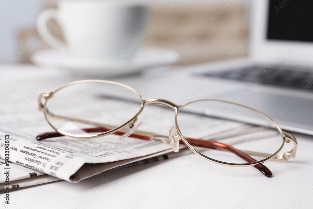 Newspapers and glasses on white table, closeup Newspapers and glasses on white table, closeup