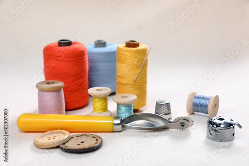 Color threads, tracing wheel and other sewing accessories on white table
