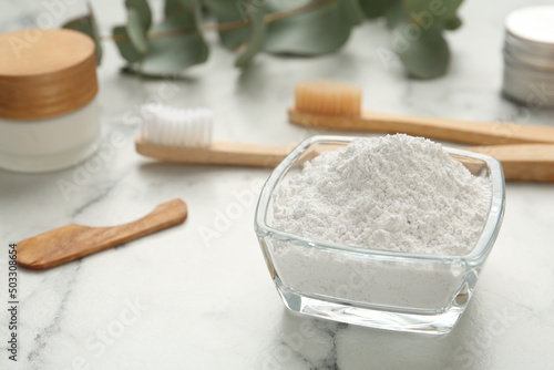 Tooth powder and brushes on white marble table, closeup