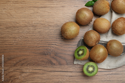 Fresh ripe kiwis on wooden table, flat lay. Space for text