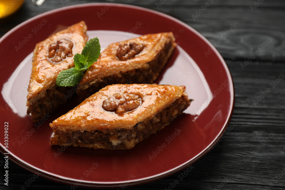 Delicious sweet baklava with walnuts and mint on black wooden table, closeup