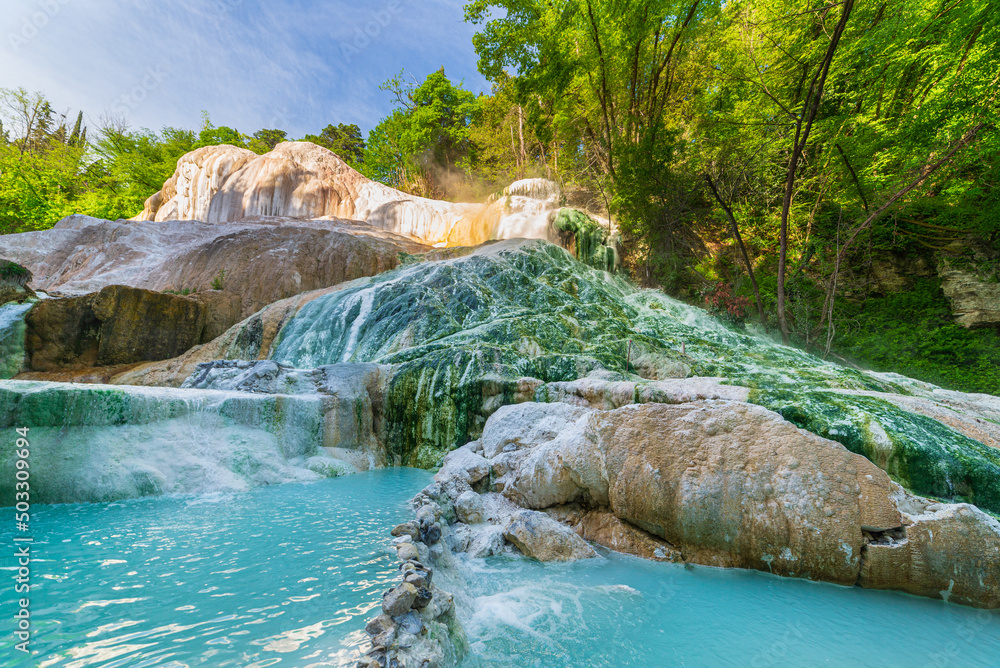 Naklejka premium Geothermal pool and hot spring in Tuscany, Italy. Bagni San Filippo natural thermal waterfall in the morning with no people. The White Whale amidst forest.