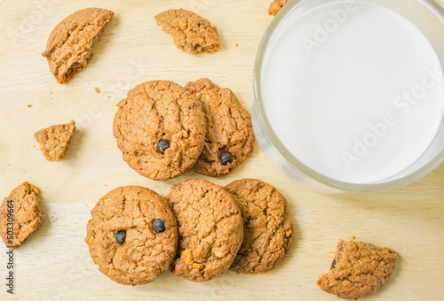 Chocolate chip cookies with glass of milk on wood plate and isolated white background. 