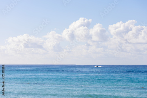 View of the Caribbean Sea in the Dominican Republic,the sea surface,the horizon and a small boat in the distance.Blue sky with clouds and ocean of beautiful color.Beautiful landscapes of the sea coast © IrinaStrelnikova