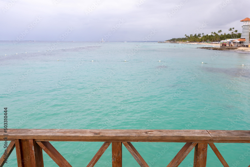 View from the pier to the beautiful sea and the sandy Caribbean coast in the Dominican Republic,lighthouse.The blue sea water and the stormy sky are separated by the horizon line.Rest in a paradise