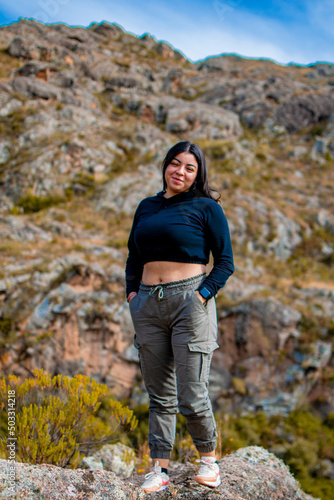 Portrait of latin woman having fun during trekking day in mountain forest posing on a rock- Front focus