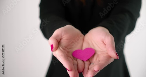 A Woman In Black Sweater Showing A Pink Heart From The Palm Of Her Hands. Close-up photo