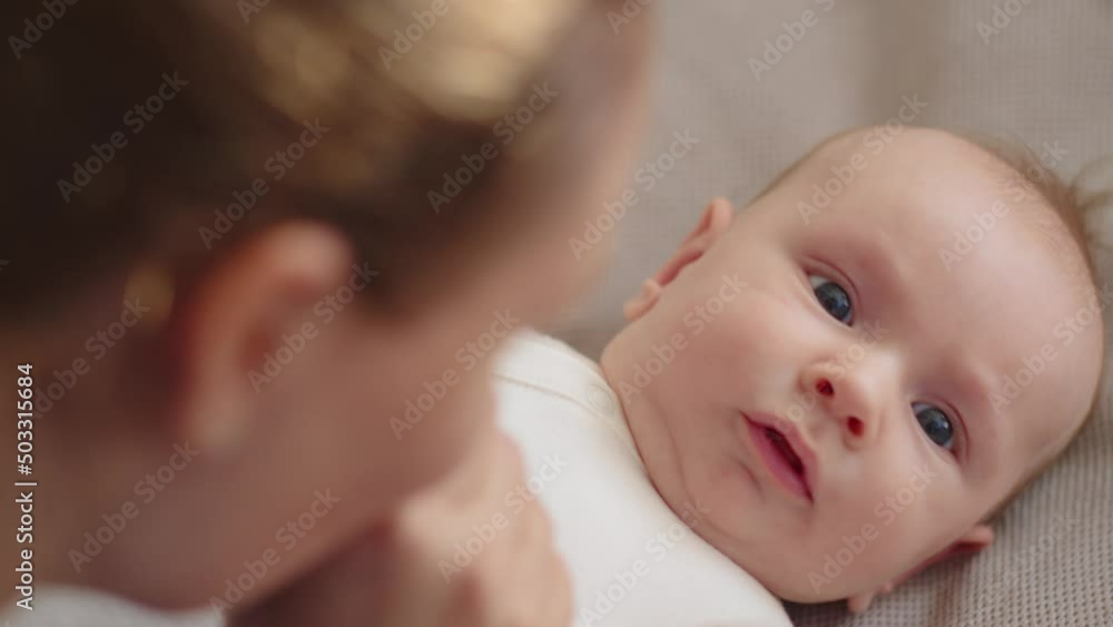 Happy mom spends time with her baby. Mother playing and kissing with a newborn baby. Face of an active baby looking at a parent. Mama is kissing her infant. motherhood and family concept. Happy mom spends time with her baby. Mother playing and kissing with a newborn baby. Face of an active baby looking at a parent. Mama is kissing her infant. motherhood and family concept.