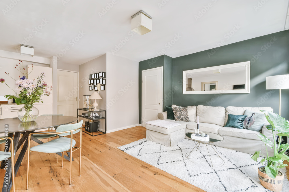 Cozy living room with comfy couch and dining table in daylight Stock