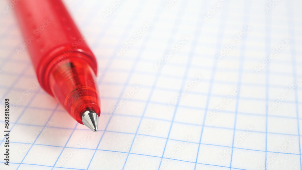Background on the theme of the new school year with place for text. Pen lies on a grid notebook sheet close-up. Light backdrop for September 1 with copy-space. Starting study and education. Macro Background on the theme of the new school year with place for text. Pen lies on a grid notebook sheet close-up. Light backdrop for September 1 with copy-space. Starting study and education. Macro