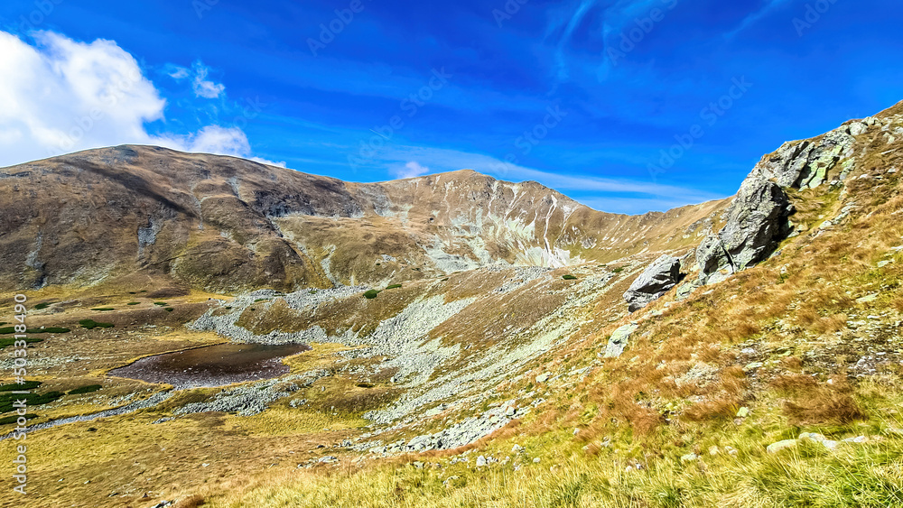 Scenic view from lake Goldlacke on yellow hills of Lower Tauern mountain range, Styria, Austria, Europe. Sunny autumn day in Seckau Alps. Scenic hiking trail to Seckauer Zinken on dry, bare terrain