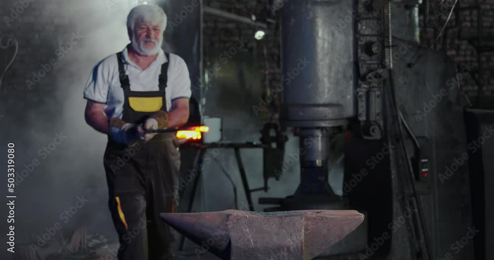 Side view of blacksmith creating metalwork in mastershop. Old skillful male red iron stick from furnace taking, putting on table, beating with hammer. Concept of forging. Side view of blacksmith creating metalwork in mastershop. Old skillful male red iron stick from furnace taking, putting on table, beating with hammer. Concept of forging.
