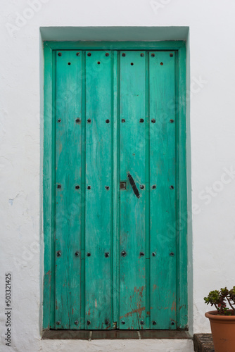 Vintage, green door with black studs and knob in Frigiliana. Malaga, Andalusia, Spain