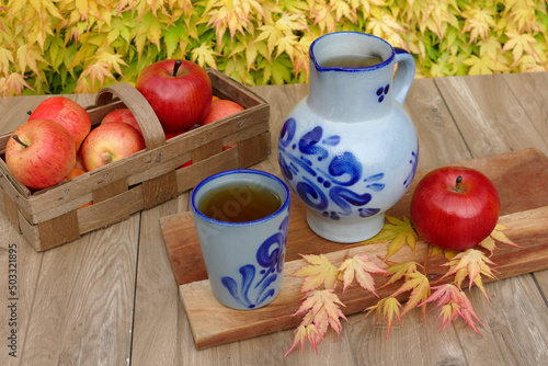 Traditioneller deutscher Apfelwein aus Hessen. Wein in einem blauen Krug vor einem Korb mit   pfeln.