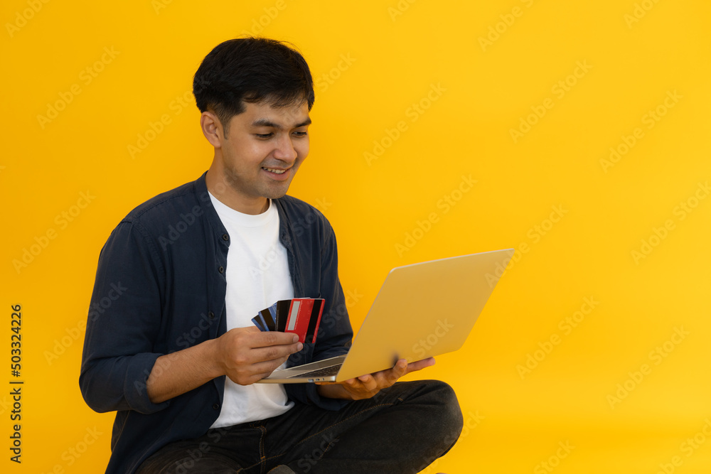Young Man holding credit card and computer laptop entering data for web-site form, going to pay for online order. People, lifestyle, modern technologies and e-commerce concept Young Man holding credit card and computer laptop entering data for web-site form, going to pay for online order. People, lifestyle, modern technologies and e-commerce concept