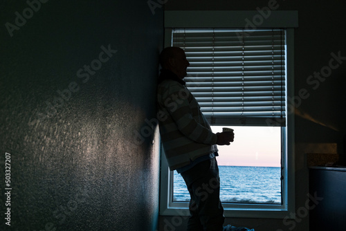 Norfolk, Virginia, USA A man drinks coffee alone in a motel room by the sea.