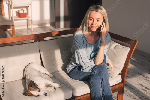 Happy 40s woman talking on mobile phone, making call from home
