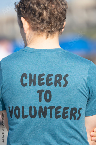 The back of a male with curly hair wearing a volunteer t-shirt. © chrt2hrt