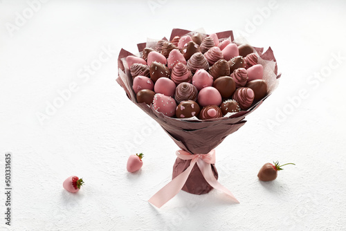 Sweet bouquet of strawberries covered with brown and pink chocolate on a white background