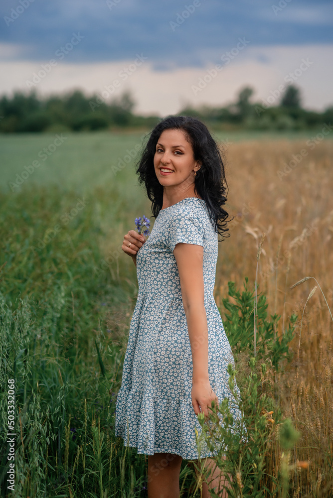 woman is standing in a field of wheat and smiling woman is standing in a field of wheat and smiling