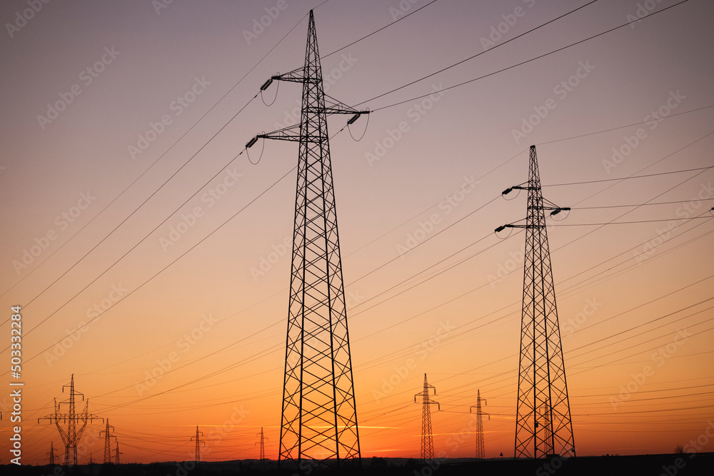 Electric power line network photographed against beautiful, winter sunset