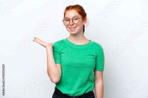Young reddish woman isolated on white background holding copyspace imaginary on the palm to insert an ad