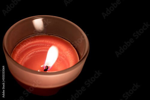 Closeup glass burning wax candle dark background