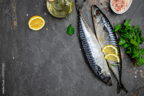 Raw Mackerel fish with salt, lemon and spices on dark background. Fresh seafood. Culinary, cooking fish concept. banner, menu, recipe place for text, top view