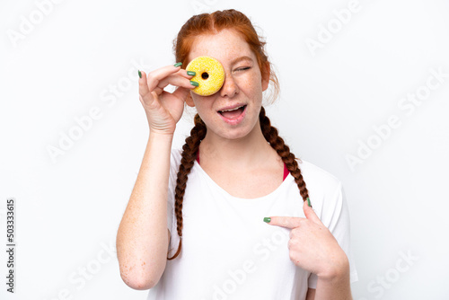 Young reddish woman isolated on white background holding a donut and happy