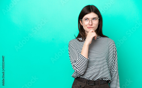Young Russian woman isolated on green background having doubts and thinking