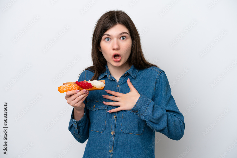 Young Russian woman holding sashimi isolated on white background surprised and shocked while looking right Young Russian woman holding sashimi isolated on white background surprised and shocked while looking right