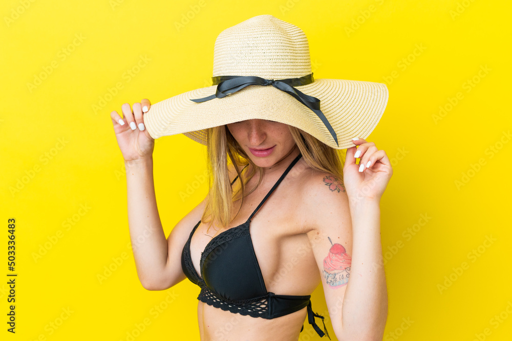 Young Romanian woman isolated on yellow background in swimsuit in summer holidays Young Romanian woman isolated on yellow background in swimsuit in summer holidays